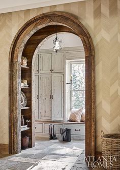 an arched doorway leads into a well lit room with white walls and wood trimmings