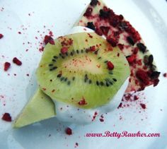 a piece of cake with kiwi on it is sitting on a white plate and has red sprinkles