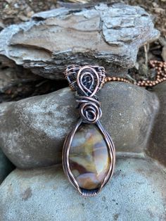 a wire wrapped pendant sitting on top of a rock