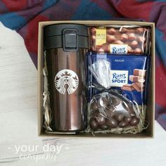 a starbucks coffee cup, chocolates and candy in a gift box on a bed