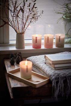 candles and books are sitting on a window sill