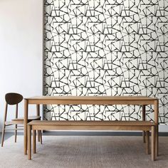 two wooden benches sitting next to each other in front of a wall with black and white designs on it