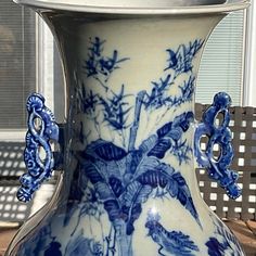 a blue and white vase sitting on top of a wooden table next to a window