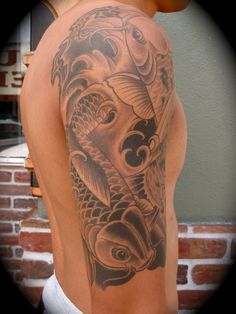 a man with a tattoo on his back showing two koi fish in the water