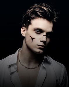 a man with makeup on his face and nose is posing for a photo in the dark