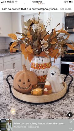 a kitchen counter top with a vase filled with pumpkins and other decorations on it