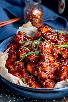 a blue plate topped with meat covered in sauce and garnished with green onions