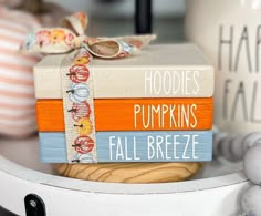 a stack of books sitting on top of a white shelf next to other items and decorations