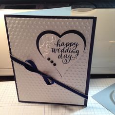 a white card with a blue ribbon and a black heart on it that says happy wedding day