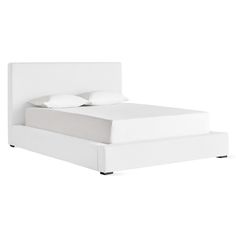 a white bed with two pillows on top of it and a night stand next to it