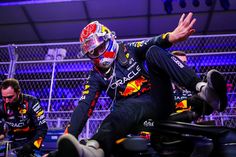 a man sitting on top of a motorcycle next to another man in a red bull suit