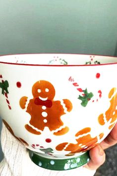 a person is holding a bowl with a gingerbread design and candy canes on it