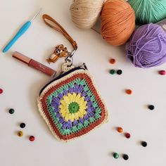 a crocheted purse sitting on top of a table next to balls of yarn