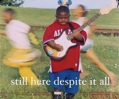 a young boy is playing the guitar in front of two other boys on train tracks