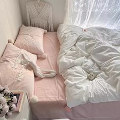 a small bed with pink sheets and pillows