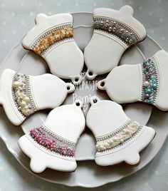 decorated cookies are arranged in the shape of hats on a white plate with silver trimmings