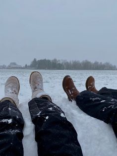 two people are sitting in the snow with their feet on each other's legs