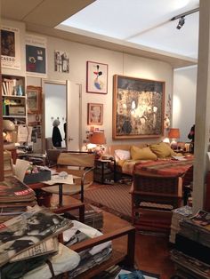 a living room filled with lots of furniture and pictures on the wall next to bookshelves