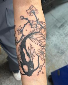 a person with a tattoo on their arm that has flowers and a fish in it