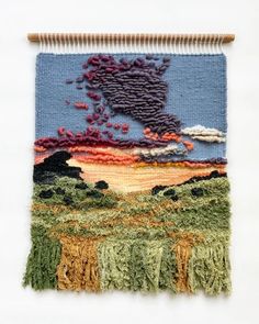 an embroidered wall hanging with various colors and designs on it, including the image of a bird flying in the sky