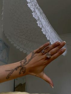 a woman's arm with tattoos on it holding something in her hand while wearing a ring