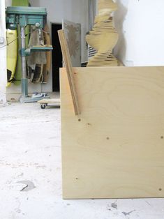 a wooden box sitting on top of a white floor next to a piece of wood