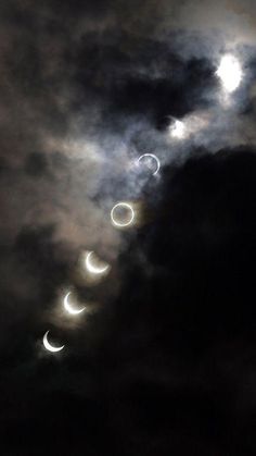 the moon is seen through clouds as it passes in front of some dark skys