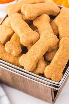 a tin filled with dog biscuits sitting on top of a table next to oranges