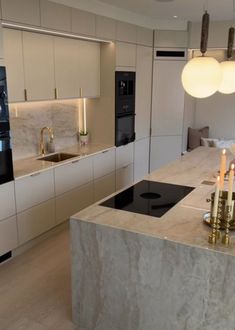 a modern kitchen with marble counter tops and gold candles on the island in front of it