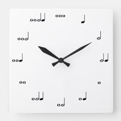 a white square clock with musical notes on the face and numbers in black, against a white background