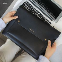 a person is holding a black bag with a laptop on it's lap top