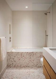 a bathroom with a bathtub, sink and shower head mounted to the side of the wall