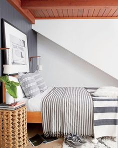 a bed sitting under a wooden ceiling next to a white and black striped comforter