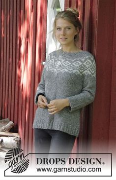 a woman standing in front of a red barn wearing a sweater and leggings