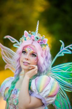 a woman dressed as a fairy holding her hand to her face and looking at the camera