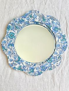 a blue and white plate sitting on top of a cloth covered table next to a mirror