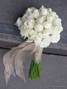 a bridal bouquet with white flowers on the side of a building in front of a window