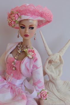 a barbie doll wearing a pink dress and hat with flowers on it's head