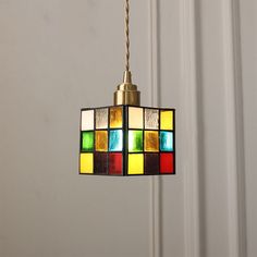 a multi - colored light fixture hanging from a ceiling in front of a white wall