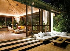 an outdoor living room with wooden floors and white furniture