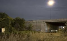 an abandoned building with a street light in the background and grass on the foreground