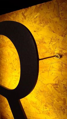 the letter q is lit up in front of a yellow wall with black letters on it