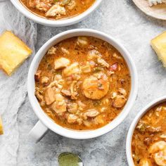 three bowls of soup on a table with bread