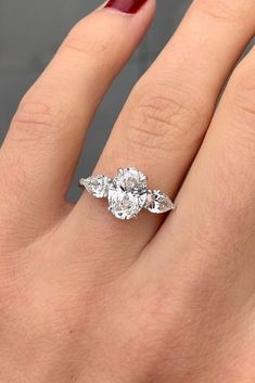 a woman's hand with a three stone ring on her left and an engagement ring on the right