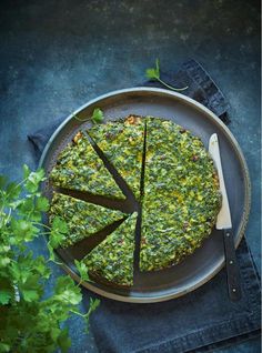 a pizza with spinach and cheese is on a plate next to a knife and fork