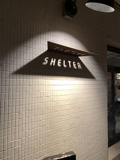 there is a sign on the wall that says shelter in white tiles and black letters