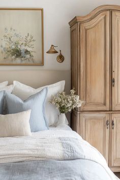 a bed with blue and white pillows on top of it next to a wooden cabinet