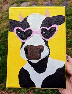 a painting of a black and white cow wearing heart shaped glasses with grass in the background