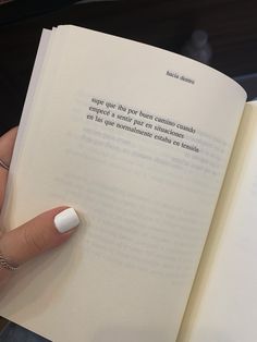 a person is holding an open book in their hand and it has writing on the page