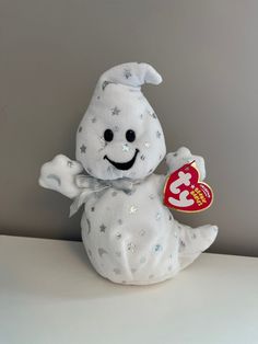 a white stuffed animal with stars on it's chest holding a heart shaped candy bar